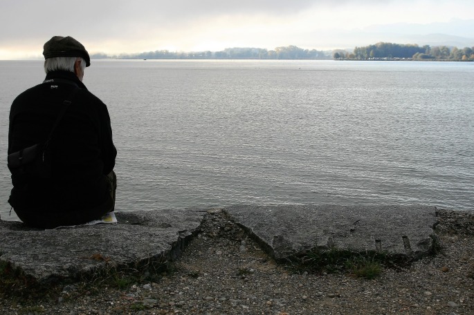 Elderly man sitting at a lake